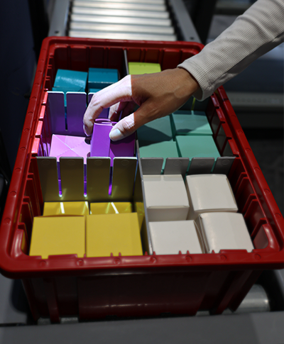 person picking from a divided tote with one section illuminated