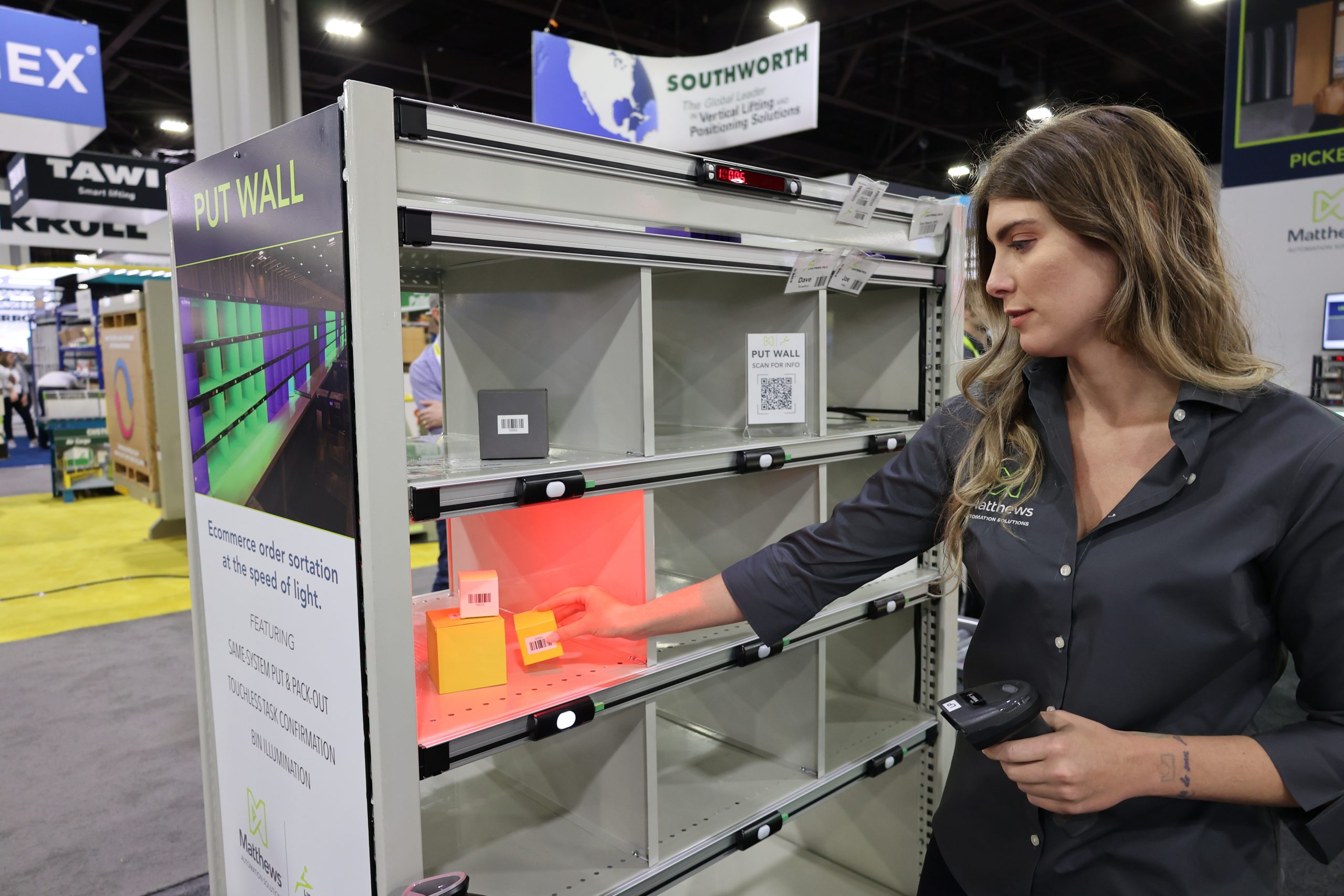 Operator performing put-to-light demo with bin illumination in a trade show booth